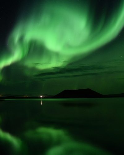 Dancing green Northern Lights above Lake Mývatn, creating a stunning spectacle in the Icelandic sky.