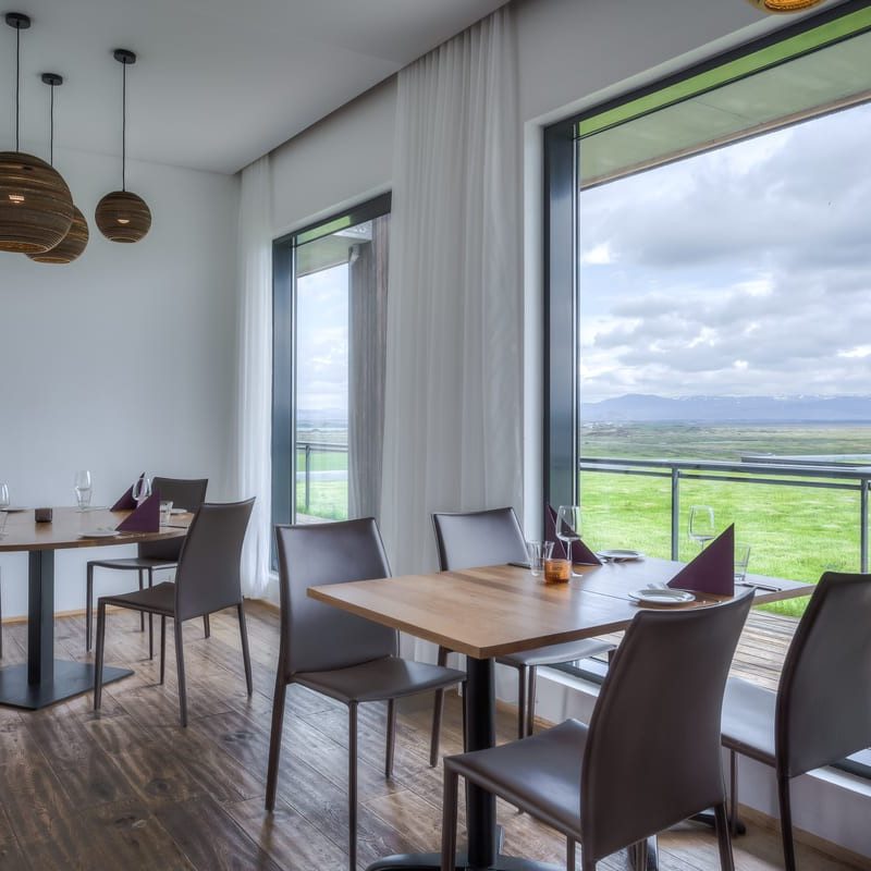 Interior of Eldey Restaurant with tables and stunning view of Lake Mývatn at Hotel Laxá.